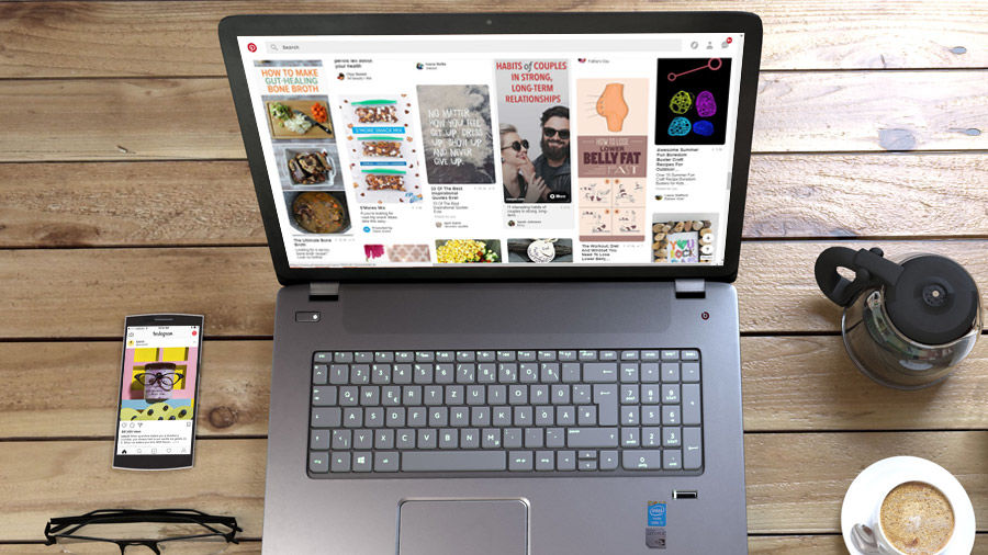 Computer with Pinterest open on screen with phone sitting on table with Instagram open on screen
