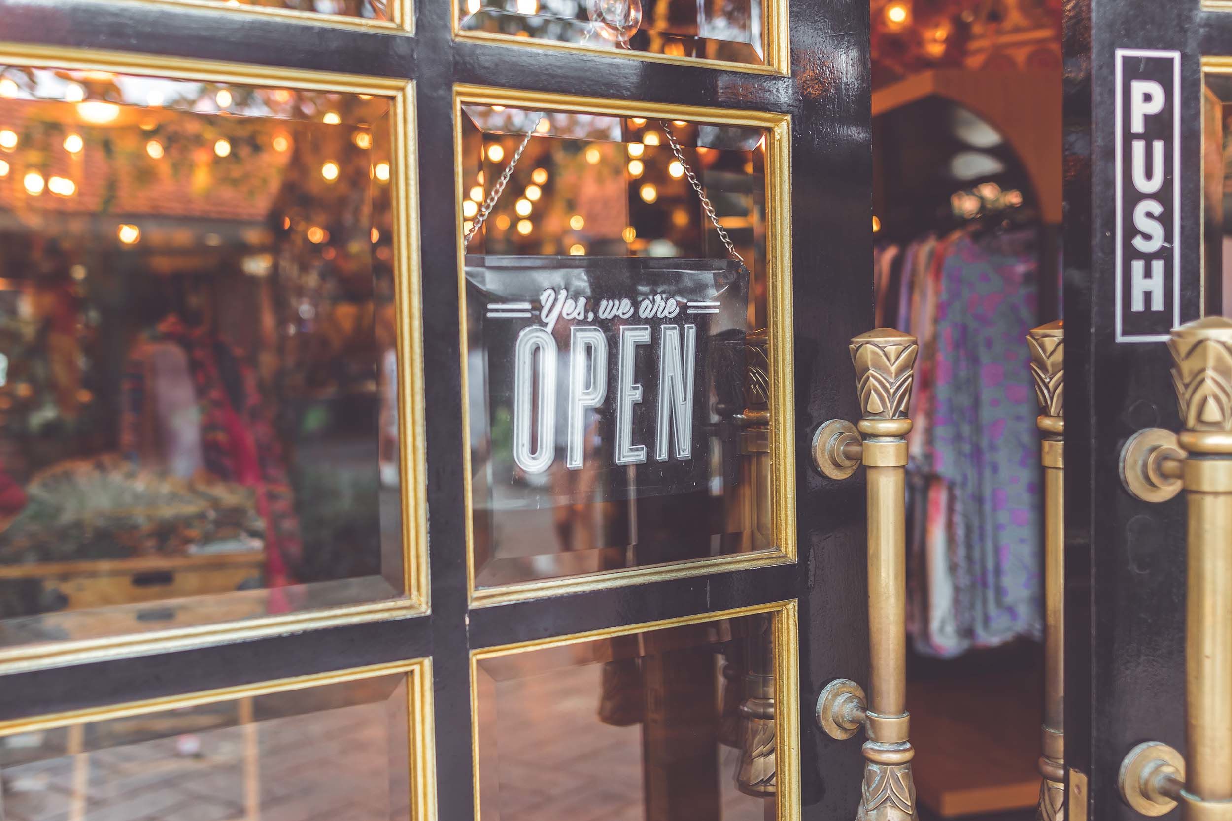 Door to small boutique clothing store with we're open sign on front door